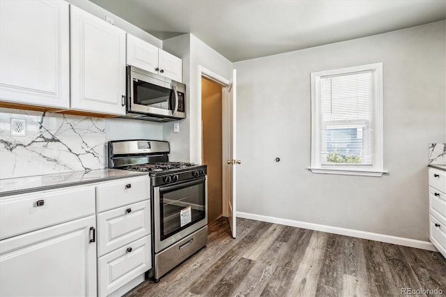 kitchen with stone counters, wood-type flooring, white cabinets, decorative backsplash, and stainless steel appliances