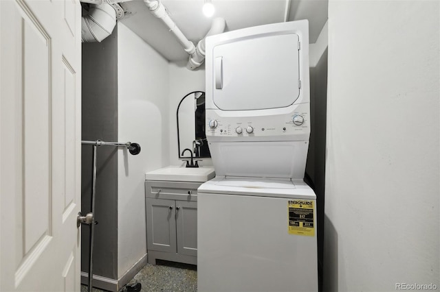 clothes washing area with stacked washer and dryer, sink, and cabinets