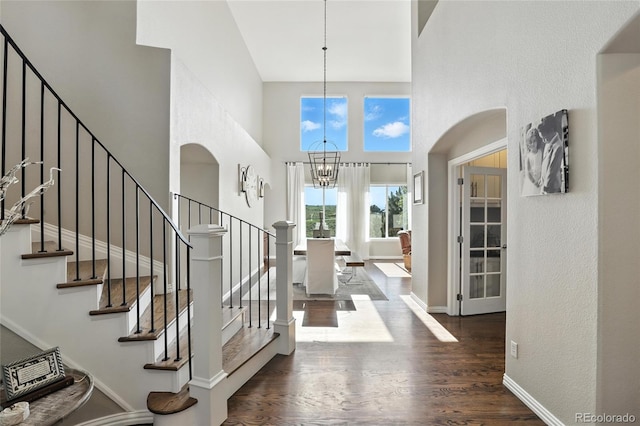 10601 Chadsworth Ln, Highlands Ranch, CO 80126 - foyer entrance featuring a high ceiling, a chandelier, wood finished floors, arched walkways, and stairs