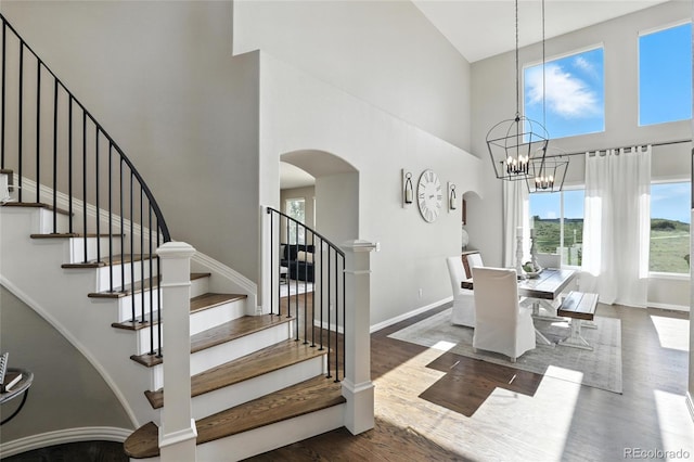 10601 Chadsworth Ln, Highlands Ranch, CO 80126 - staircase featuring a towering ceiling, arched walkways, wood finished floors, and a chandelier