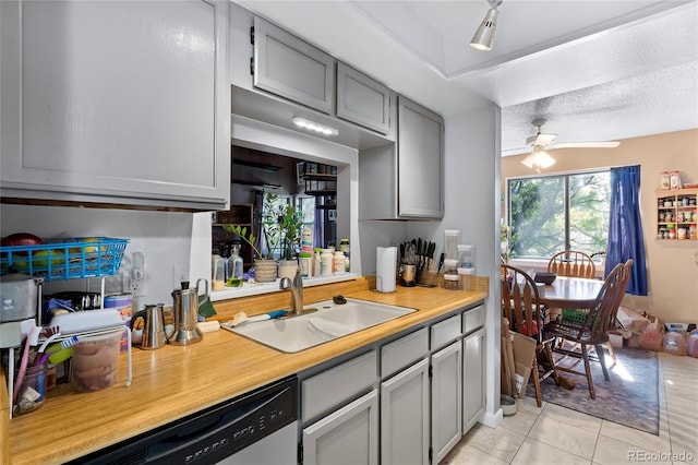 kitchen with a textured ceiling, light tile patterned flooring, dishwasher, ceiling fan, and sink