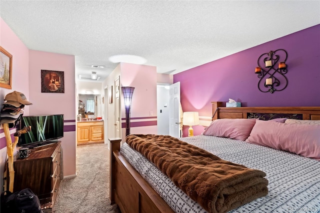 bedroom featuring light carpet, a textured ceiling, visible vents, and ensuite bathroom