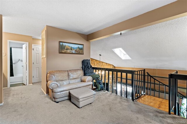 carpeted living room featuring vaulted ceiling with skylight and a textured ceiling