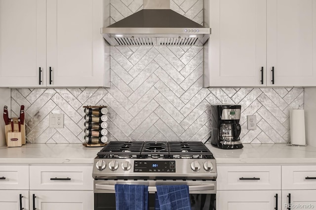 kitchen featuring gas range, white cabinets, and wall chimney range hood