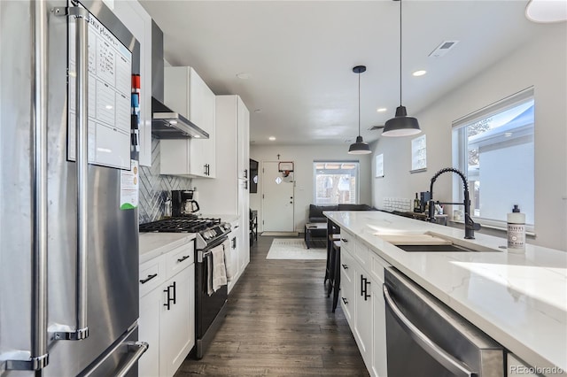 kitchen featuring dark wood-type flooring, a sink, stainless steel appliances, decorative backsplash, and light stone countertops