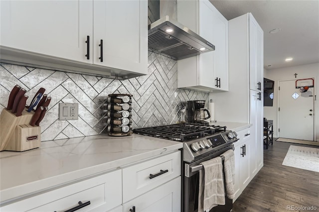 kitchen with wall chimney range hood, stainless steel range with gas stovetop, light stone counters, dark wood-style floors, and white cabinetry