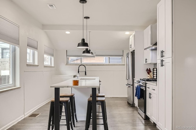 kitchen featuring visible vents, under cabinet range hood, stainless steel appliances, white cabinetry, and a sink