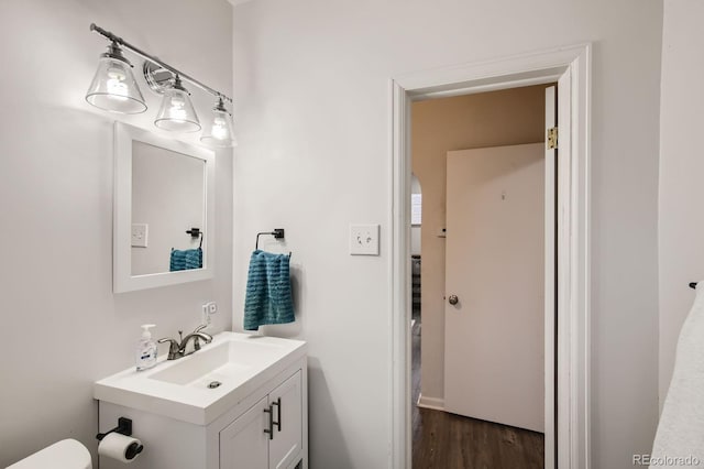 half bathroom featuring toilet, wood finished floors, and vanity