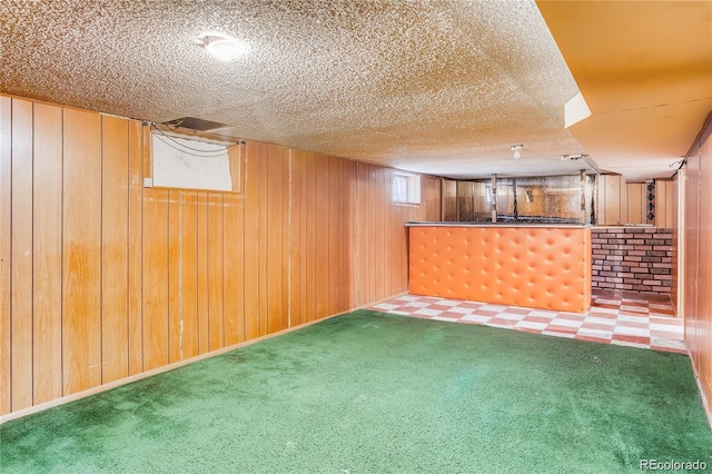 finished below grade area featuring carpet flooring, wood walls, and a textured ceiling