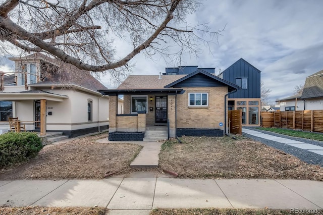 bungalow-style house featuring brick siding and fence