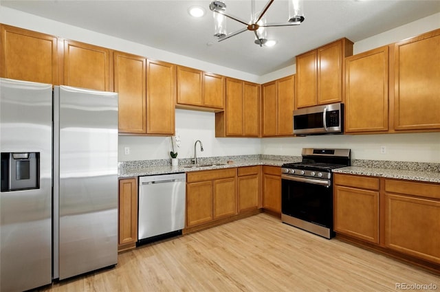 1881 S Dunkirk St Unit 106, Aurora, CO 80017 - kitchen with light stone countertops, appliances with stainless steel finishes, an inviting chandelier, a sink, and light wood-style flooring