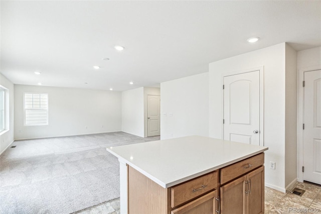20724 E 57th Ave, Aurora, CO 80019 - kitchen featuring recessed lighting, light countertops, brown cabinetry, a center island, and light carpet