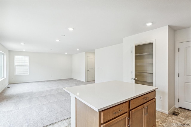 20724 E 57th Ave, Aurora, CO 80019 - kitchen with light countertops, recessed lighting, a kitchen island, brown cabinets, and light carpet