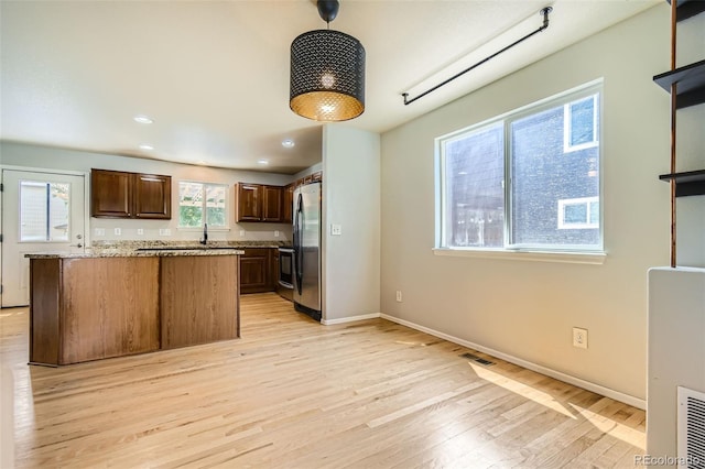 13018 Niagara Way, Thornton, CO 80602 - kitchen with freestanding refrigerator, light wood finished floors, dark brown cabinetry, light stone countertops, and recessed lighting