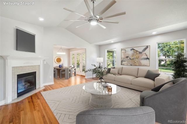 living room with ceiling fan, vaulted ceiling, and light hardwood / wood-style flooring