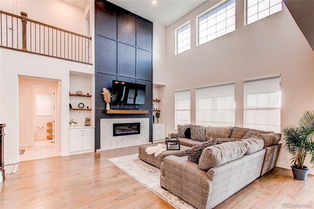 8107 Arapahoe Peak St, Littleton, CO 80125 - living area featuring a high ceiling, light wood-style floors, a premium fireplace, and built in features