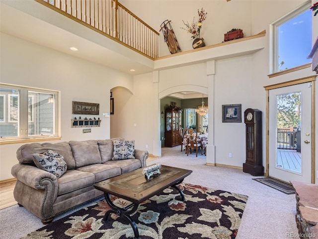 living room with a towering ceiling and light colored carpet