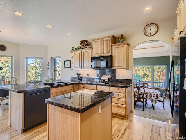 kitchen with sink, a center island, black appliances, a healthy amount of sunlight, and light brown cabinetry