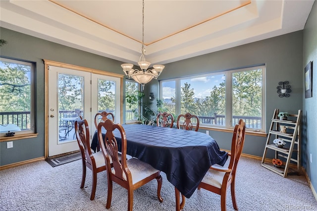 carpeted dining space with a raised ceiling and a chandelier