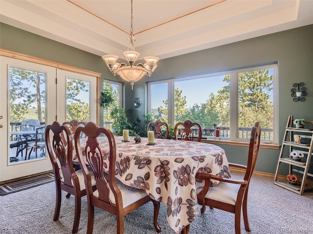 dining room with carpet flooring, a raised ceiling, and a notable chandelier