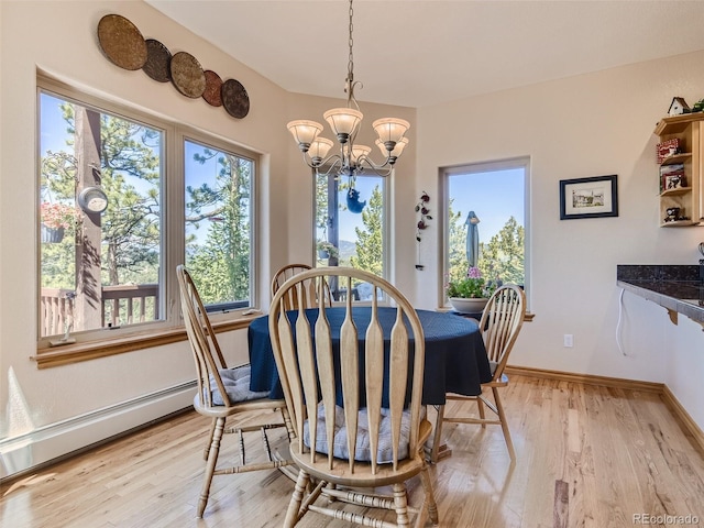 dining space with light hardwood / wood-style flooring, a baseboard radiator, and a chandelier