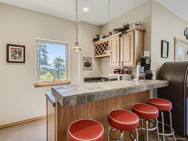 kitchen with sink, carpet floors, a kitchen breakfast bar, kitchen peninsula, and light brown cabinets