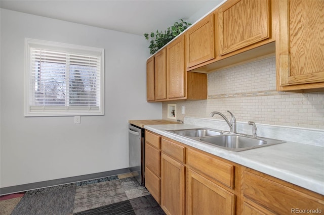 kitchen featuring a sink, backsplash, stainless steel dishwasher, light countertops, and baseboards