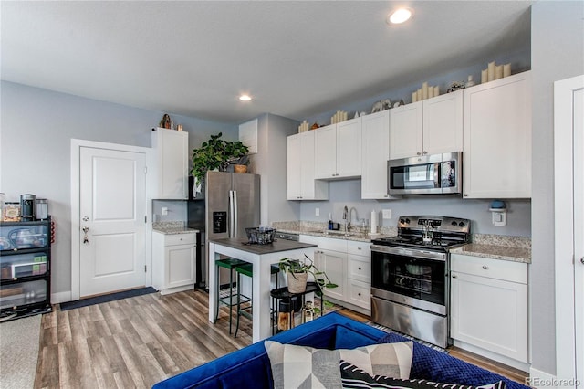 kitchen featuring light wood finished floors, white cabinetry, appliances with stainless steel finishes, and a sink