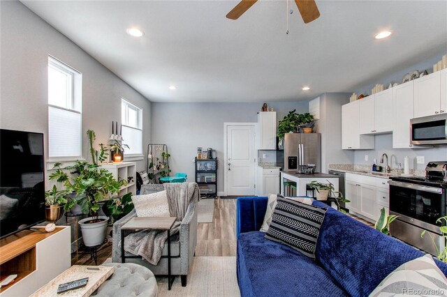 living area with light wood-style flooring, a ceiling fan, and recessed lighting