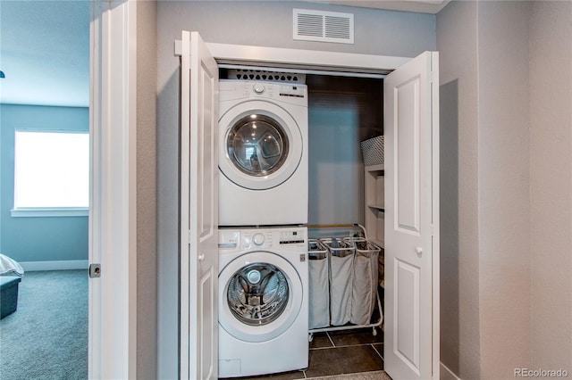 washroom with carpet, visible vents, stacked washing maching and dryer, tile patterned flooring, and laundry area