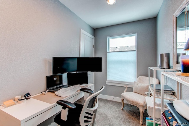 carpeted office featuring a textured wall and baseboards