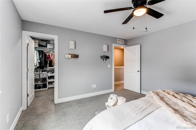 bedroom with visible vents, baseboards, a walk in closet, carpet floors, and a closet