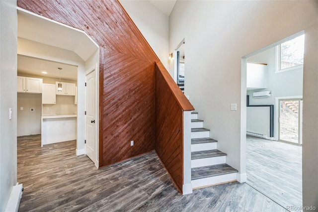 stairs with a wall mounted air conditioner and hardwood / wood-style flooring