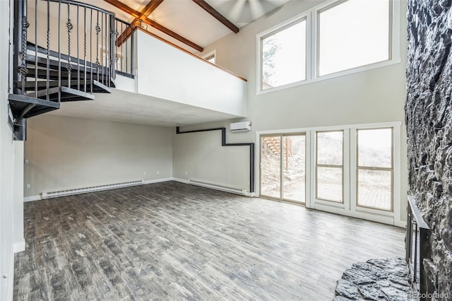 unfurnished living room featuring hardwood / wood-style flooring, a high ceiling, a baseboard heating unit, and a wall mounted air conditioner