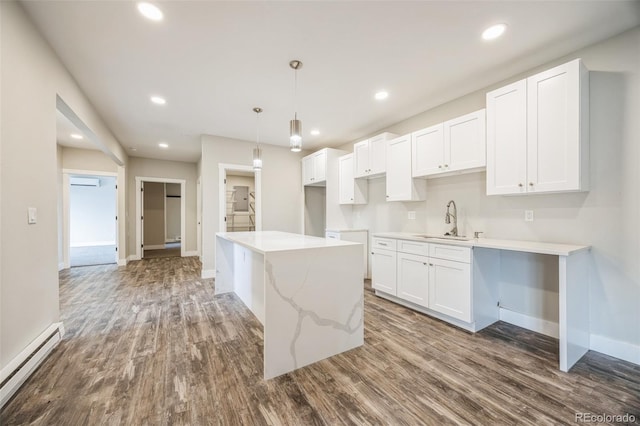 kitchen with pendant lighting, sink, a baseboard heating unit, white cabinets, and a kitchen island