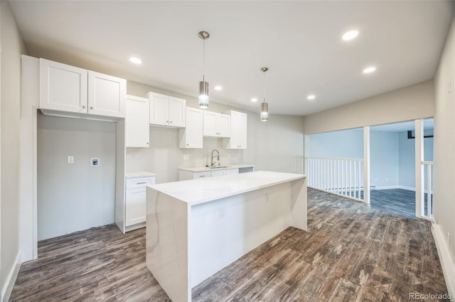 kitchen with a kitchen island, decorative light fixtures, white cabinets, dark hardwood / wood-style flooring, and light stone countertops