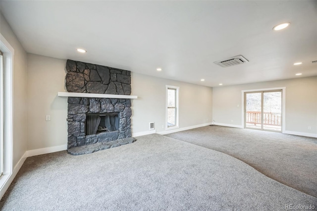 unfurnished living room featuring a stone fireplace and carpet flooring