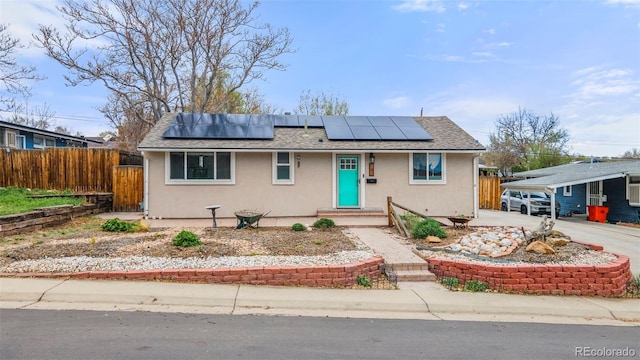 view of front of property featuring fence, roof mounted solar panels, and stucco siding