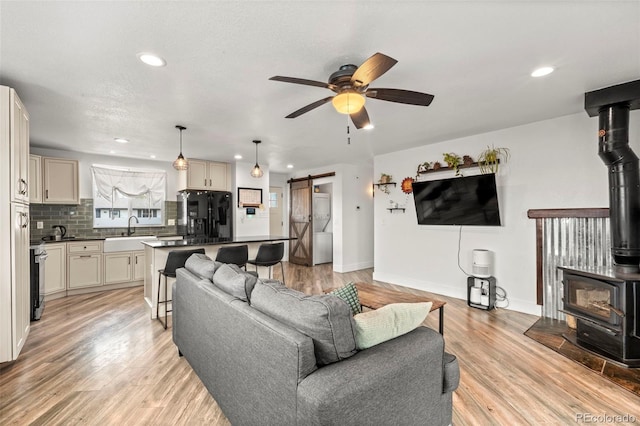 living area featuring recessed lighting, a wood stove, ceiling fan, and a barn door