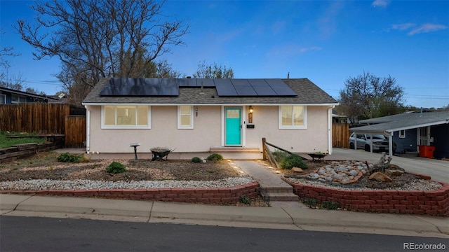 741 Cortez St, Denver, CO 80221 - view of front facade with fence, solar panels, a shingled roof, and stucco siding