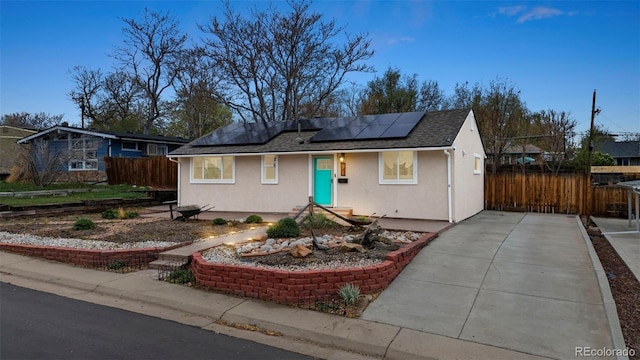 741 Cortez St, Denver, CO 80221 - single story home featuring fence, stucco siding, a shingled roof, roof mounted solar panels, and concrete driveway