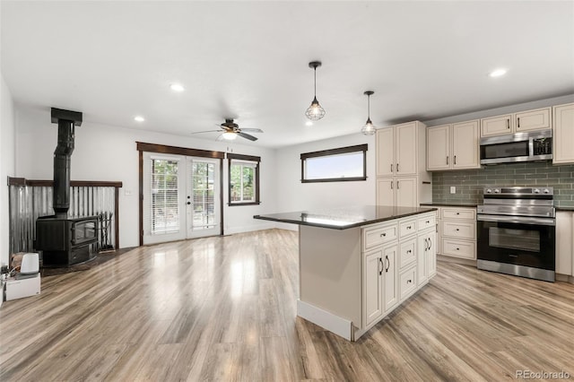 741 Cortez St, Denver, CO 80221 - kitchen with stainless steel appliances, light wood-style floors, a wood stove, open floor plan, and recessed lighting