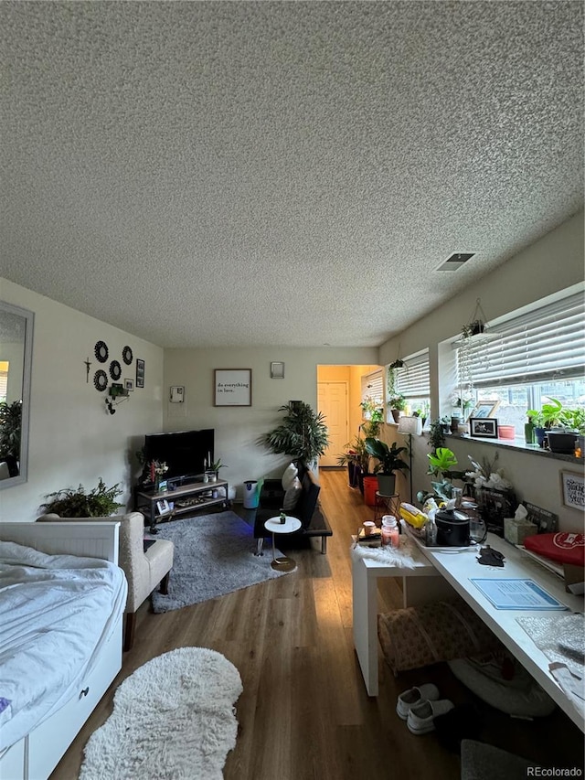 living room featuring visible vents, a textured ceiling, and wood finished floors