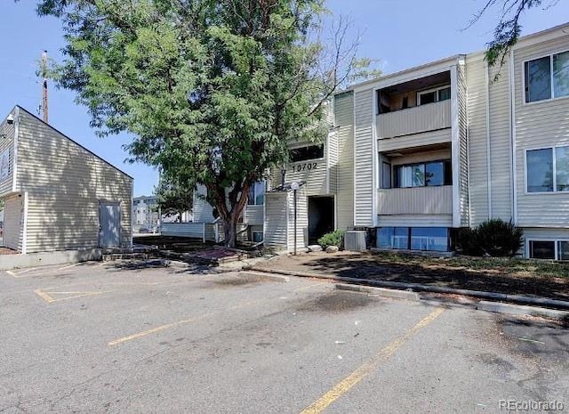 view of building exterior featuring uncovered parking and cooling unit