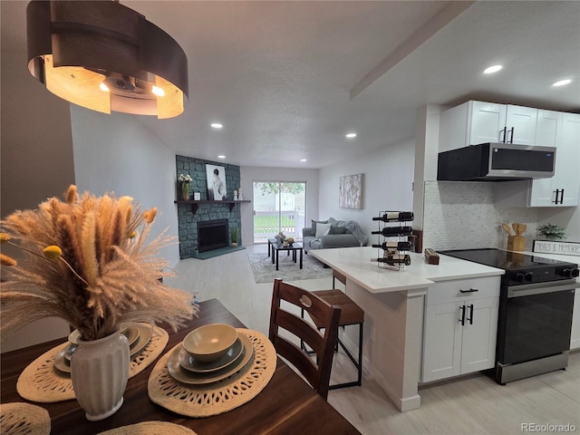 14433 E Jewell Ave Unit 101, Aurora, CO 80012 - kitchen featuring electric range, stainless steel microwave, light wood finished floors, decorative backsplash, and a stone fireplace