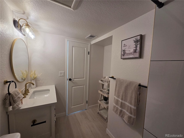 14433 E Jewell Ave Unit 101, Aurora, CO 80012 - bathroom featuring wood finished floors, vanity, and a textured ceiling
