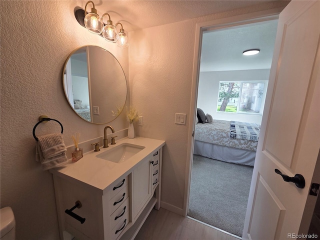 14433 E Jewell Ave Unit 101, Aurora, CO 80012 - ensuite bathroom featuring vanity, a textured wall, and wood finished floors