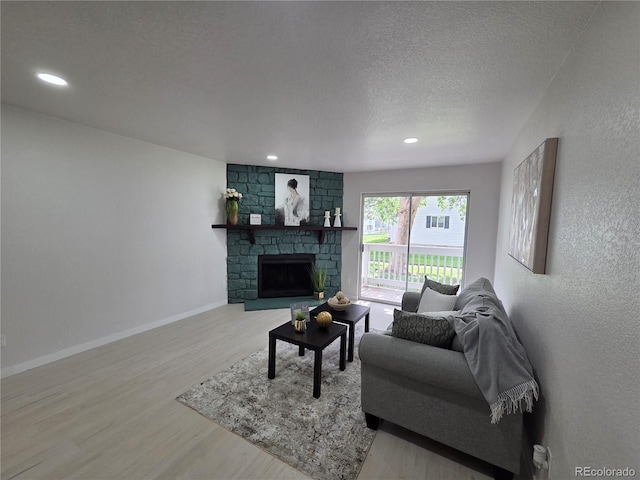 14433 E Jewell Ave Unit 101, Aurora, CO 80012 - living room featuring wood finished floors, a textured ceiling, a stone fireplace, recessed lighting, and a textured wall