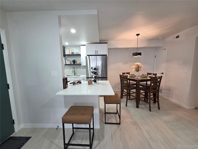 14433 E Jewell Ave Unit 101, Aurora, CO 80012 - kitchen with stainless steel refrigerator, a breakfast bar, light wood finished floors, open shelves, and light countertops