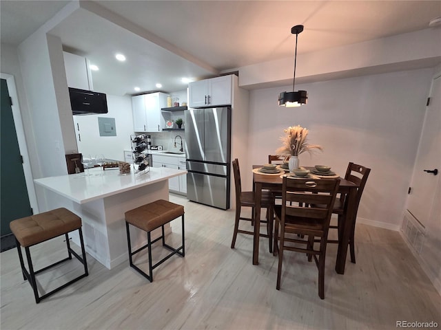 14433 E Jewell Ave Unit 101, Aurora, CO 80012 - kitchen with freestanding refrigerator, open shelves, white cabinets, a kitchen bar, and light wood finished floors